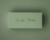 Olive green flat place card with black ink printed name in a modern script font.