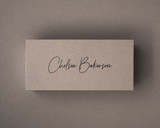 Mocha flat place card printed in sleek black ink with elegant handwritten font, set against a taupe backdrop.