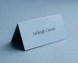 Personalised dusty blue folded place card with black ink name printing for elegant wedding place settings