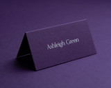 Personalised aubergine folded place card with white ink printing, displaying guest name in elegant font.