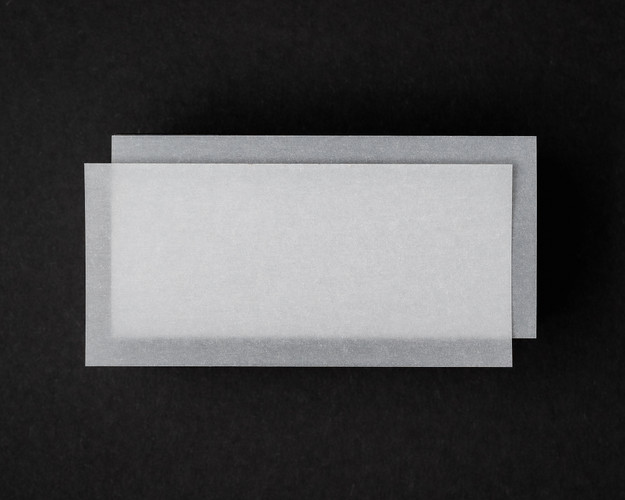 Set of translucent vellum flat place cards stacked on a dark background