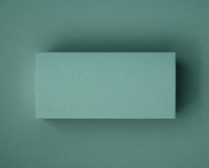 A close-up of a blank jade green flat place card, photographed on matching coloured paper. This image showcases the smooth matte finish and natural texture of the 300gsm cardstock — perfect for elegant table styling at weddings, events or private dinners.