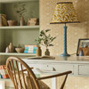 Morris & Co Borage Wallpaper 217197 Sunflower close up in a study setting with desk, books, plants and coordinating patterned lampshade
