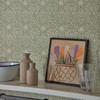 Morris & Co Borage Wallpaper Leafy Arbour close up showing floral pattern behind kitchen shelf with framed artwork and ceramics