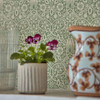 Morris & Co Borage Wallpaper Leafy Arbour close up showing floral pattern with potted plant and glassware in foreground