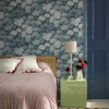 Bedroom interior featuring Little Greene Rhododendron Walk wallpaper in Hicks’ Blue with pale florals against a deep blue wall