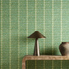 Harlequin Toluca Moss Turquoise wallpaper styled behind a wooden console table, highlighting green and turquoise vertical stripe design.