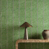Harlequin Toluca Forest Onyx wallpaper styled behind a wooden console table, showcasing bold vertical green and black stripe design.
