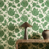 Harlequin Zamora Forest wallpaper styled behind a wooden console table, showcasing bold green floral design.