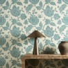 Harlequin Zamora Seaglass wallpaper styled behind a wooden console table, highlighting bold floral design in calming green tones.