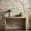 Harlequin Pintura Majorelle Spice Forest wallpaper styled behind a wooden console table, showcasing vibrant painterly brushstrokes.