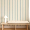Scion Fondant Stripe Denim wallpaper styled behind a wooden bench highlighting blue striped pattern.