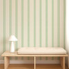 Scion Fondant Stripe Jade wallpaper styled behind a wooden bench showing soft green striped pattern.
