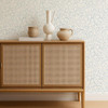 Scion Flo Swirl Cornflower wallpaper behind a rattan-front cabinet, highlighting delicate swirl pattern.