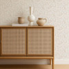 Scion Dove & Deer Pebble wallpaper behind a rattan-front cabinet, showing delicate nature-inspired pattern.