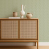 Scion Triangle Trellis Kelly Green wallpaper behind a rattan-front cabinet, showcasing delicate green geometric repeat.