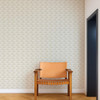 Scion Hares Pebble wallpaper used as a feature wall behind a wooden chair, highlighting neutral running hare design.