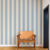 Scion Central Stripe Cornflower wallpaper styled as a feature wall behind a wooden chair, showcasing soft blue vertical stripes.