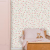 Little Dutch Fairy Wonders Multicolour wallpaper behind wooden toddler bed with pink bedding.