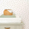 Little Dutch Blueberry Leaves White Green wallpaper styled with wicker basket and changing mat in nursery.