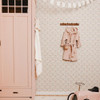 Little Dutch Fairy Flowers Pink Green wallpaper styled in a nursery with pink wardrobe and child’s robe on wall hooks.