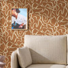 Made Varri Burnt Orange wallpaper styled behind cream sofa with abstract looping line design.