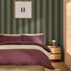 Made Demi Moss Wide Stripe wallpaper in bedroom with bold green striped feature wall.