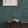 Made Shae Teal Limewash wallpaper styled behind dark wood dresser with framed artwork.