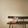 Romo Zenya wallpaper tawny textured wall in neutral interior with wooden bench and decorative bowl