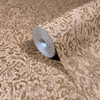 brown wallpaper roll with gold floral pattern showing textured shimmer finish