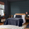 midnight floral wallpaper in bedroom with bed, wooden furniture and soft furnishings