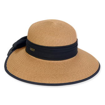 Three-quarter view of a tan woven straw sun hat featuring a rounded crown and a navy blue ribbon band with a side bow.