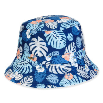 Three-quarter view of a navy blue bucket hat featuring light blue tropical monstera leaf patterns and gold metallic logo hardware