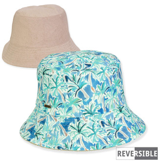 Front view of reversible bucket hat showing plain beige side and blue‑green tropical palm‑leaf patterned side with small reversible label.