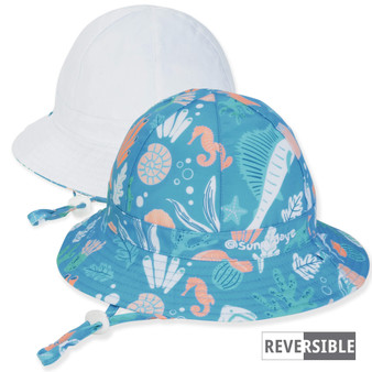 Three-quarter view of a reversible kids' bucket hat featuring a teal seahorse print side and a solid white side.