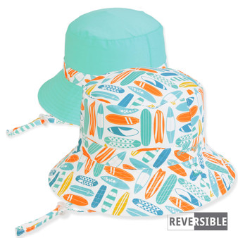 Three-quarter view of a reversible kids' bucket hat featuring a surfboard print side and a solid teal side with chin-straps.