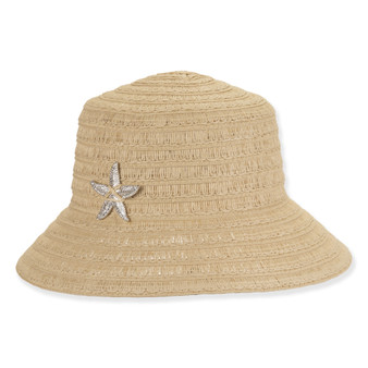Front view beige woven bucket hat with wide brim, textured straw pattern, thin brown band, rounded crown, and small metallic brand tag.