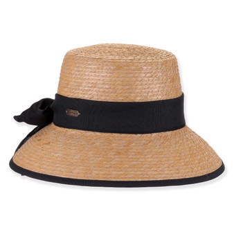 Three-quarter profile view of a natural-toned woven straw bucket hat featuring a flat crown, black fabric band, and metal logo.