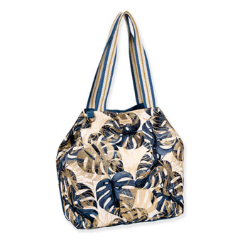 side view of a slouchy canvas tote bag featuring a navy and gold monstera leaf print with striped shoulder straps.