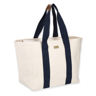 three quarters view of Sun 'N' Sand cream canvas tote, featuring navy blue vertical webbing straps and a gold metal logo.