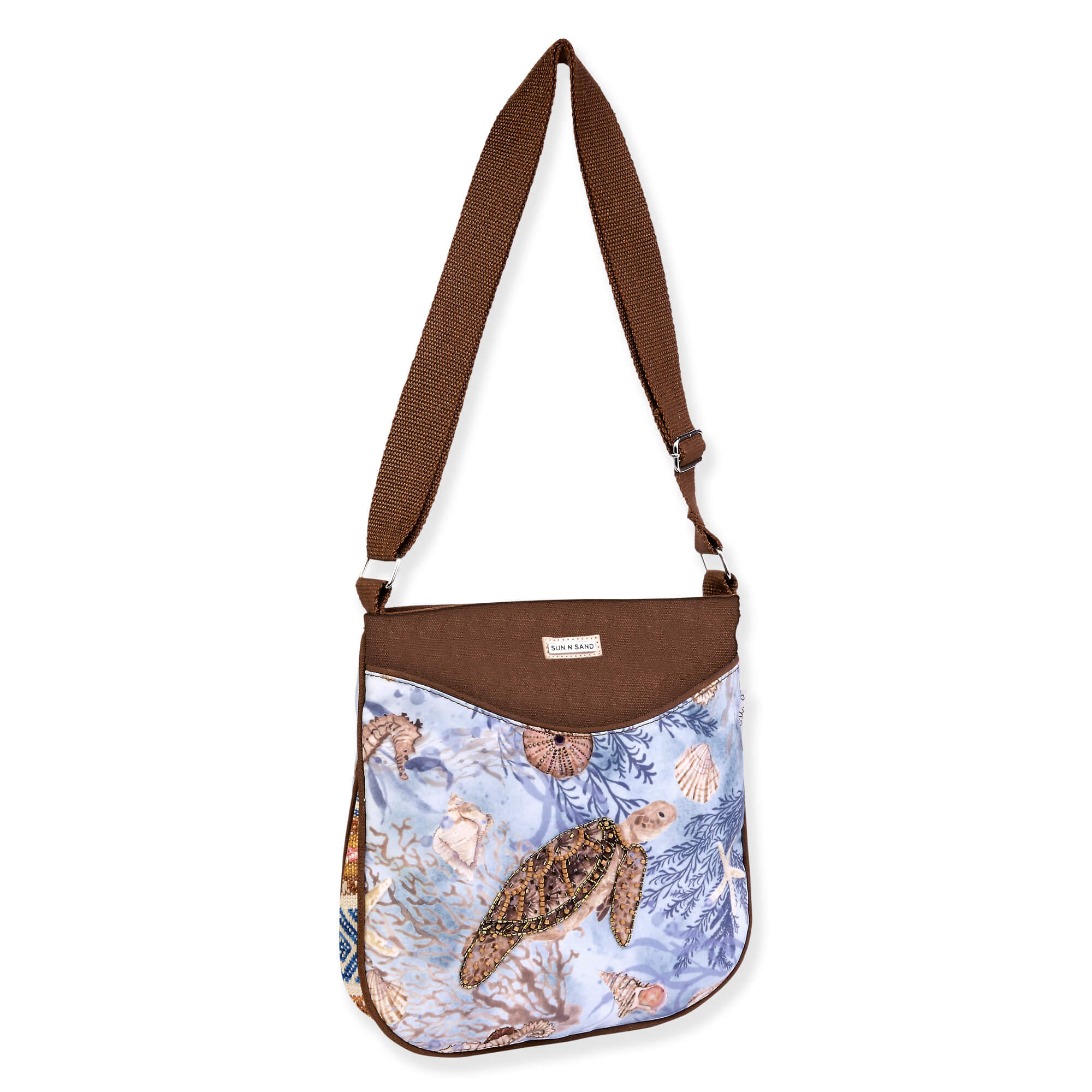 Light blue crossbody bag with illustrated sea turtle motif, curved flap pocket, zippered opening, adjustable brown shoulder strap, angled side view