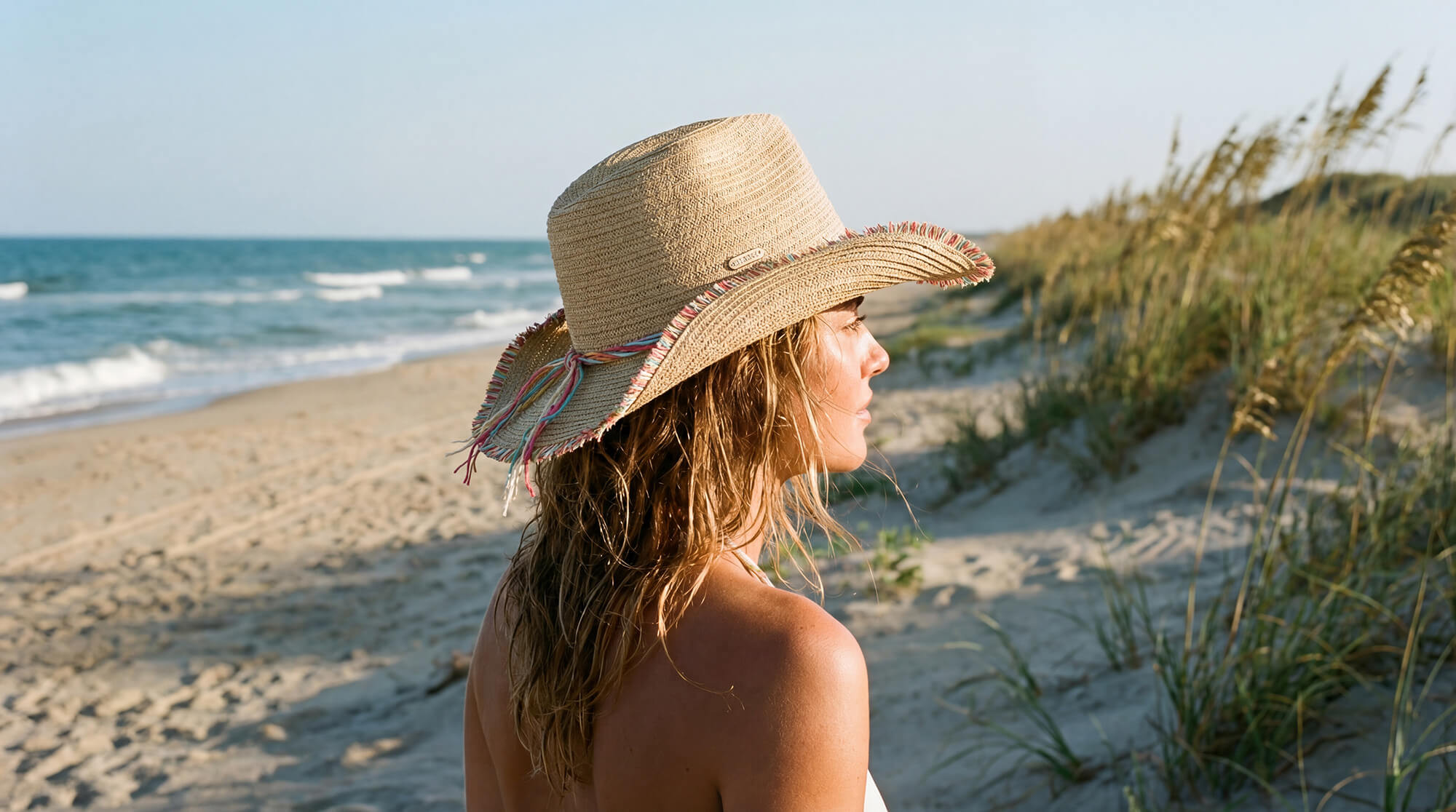 Product studio shot of the Sun N Sand HH3523 Women’s Western Hat in natural-toned woven straw, featuring a vibrant multi-color twisted hatband and a frayed-edge upturned brim for an adjustable fit and UPF 50+ sun protection.