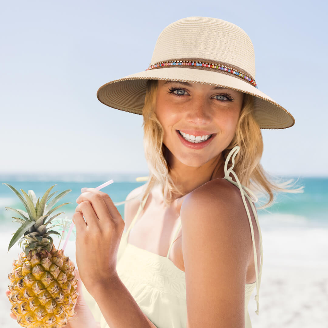 Lifestyle portrait of the Sun N Sand HH3560 Women’s Tapered Bucket Hat in a natural-toned woven straw, featuring a decorative multicolored beaded hatband and a structured, down-sloping brim for an adjustable fit and UPF 50+ sun protection.