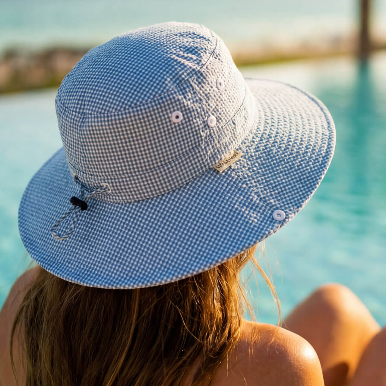 Lifestyle portrait of the Sun N Sand HH3597 Women’s Boonie Hat in a stone-colored tech fabric, featuring a breathable mesh crown, a matching chin cord with a clear toggle, and a wide, structured flat brim for an adjustable fit and UPF 50+ sun protection.