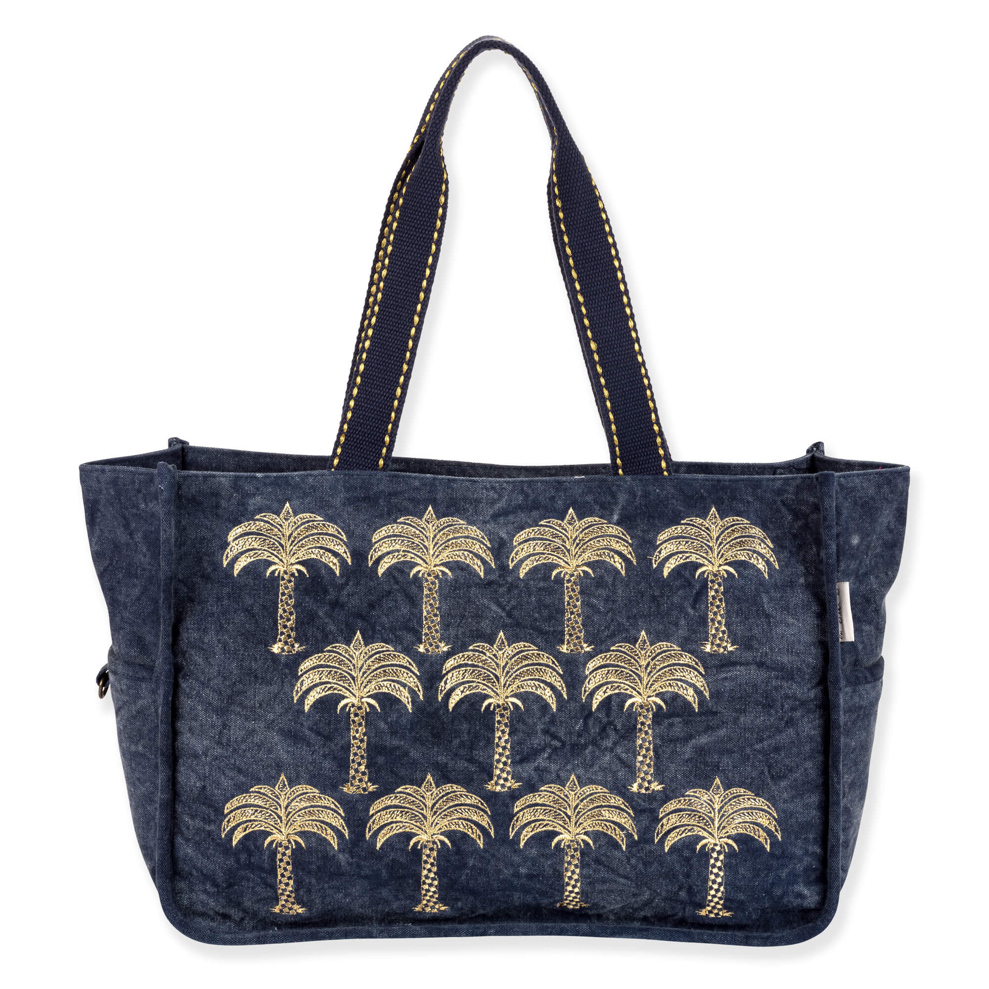 Front view of a navy quilted fabric tote bag featuring embroidered gold palm trees, woven handles, and silver-toned side hardware.