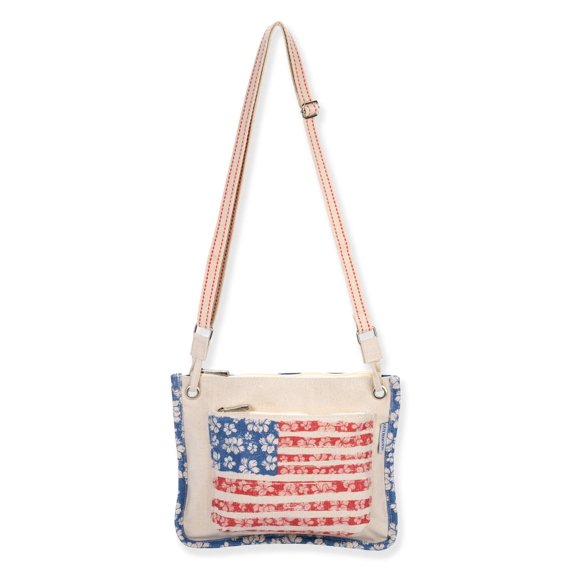 Front view of beige Guy Harvey American flag crossbody bag featuring canvas texture, hibiscus-patterned stars and stripes, and adjustable strap.