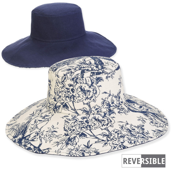 Product view of a reversible sun hat showing navy canvas and blue toile floral patterns with a wide, flexible brim.
