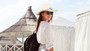 A young woman at a sunny beach resort wearing a white shirt and the cream concho straw cowboy hat from image_49639c.png.