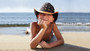 Lifestyle view of a child on a beach wearing a straw western hat with an American flag star crown.