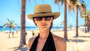 Lifestyle portrait of the Sun N Sand HH3454 A Women’s Gambler Hat in a natural tan paperbraid weave, featuring a dark patterned leopard-print hatband and a structured flat crown with a slightly upturned brim for an adjustable fit and UPF 50+ sun protection